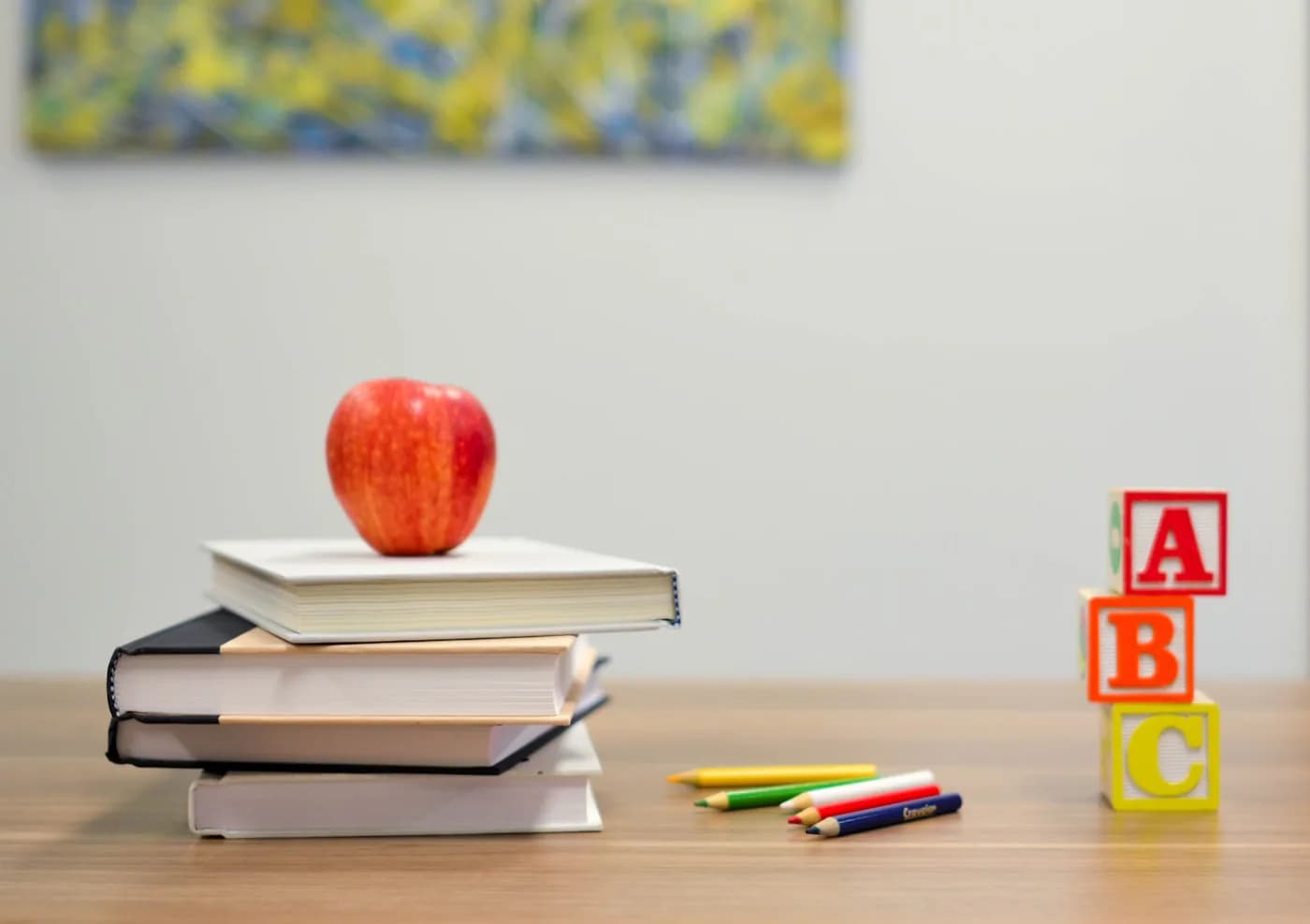 School books, pencils and an apple arranged on a desk