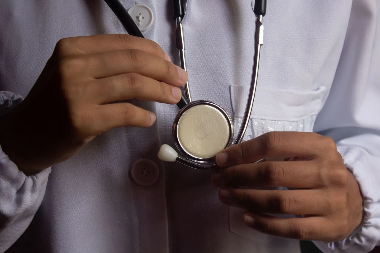 A healthcare professional in a white coat holding a stethoscope.